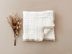 Detail of 6-layer white cotton muslin baby blanket with delicate beige lace trim edges
