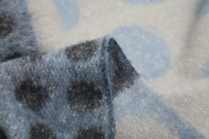Dettaglio macro di una sciarpa a pois blu e grigi in tessuto felpato morbido e spesso