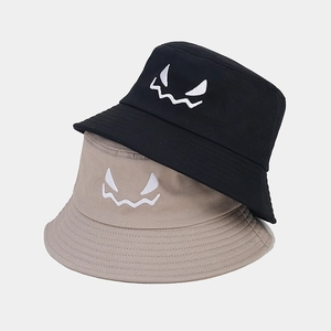 Close-up of fine embroidery showing a monster face on cotton bucket hats in two colors