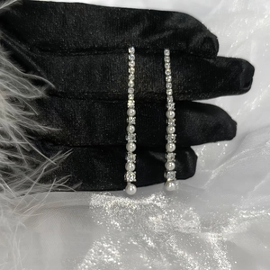 Sparkling silver tassel earrings with cubic zirconia and pearls on black glove