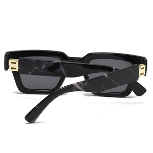 Detail of square sunglasses featuring marble pattern temples and gold hinge accents