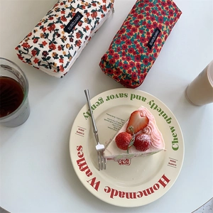 Flat lay of vintage floral corduroy pouches with merci paris tag on white table