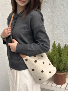 Borsa a secchiello in lana a pois con tracolla caramello indossata a tracolla dalla modella