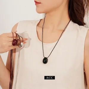 Minimalist pebble pendant necklace on black wax cord in black, red, and silver colors