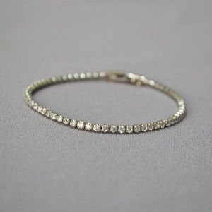 Macro shot of silver-plated tennis bracelet with sparkling cubic zirconia on grey background