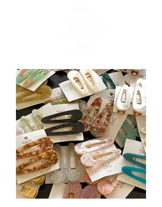 Close-up of acetate teardrop hair clips in marble and glitter patterns on display cards