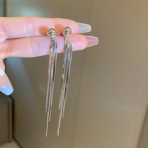 Detail of silver long tassel earrings with snake chains and polished metal sphere studs