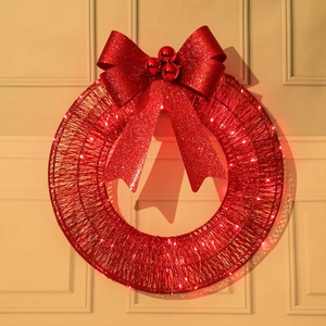Close-up of red glitter Christmas wreath with a large bow and warm white LED lights