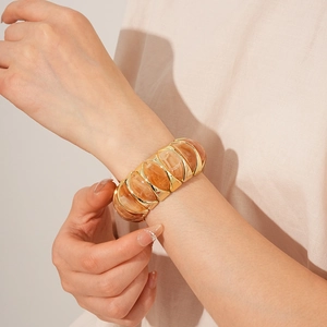 Detailed close-up of a wide vintage gold-tone bracelet featuring amber resin segments