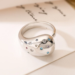 Artistic silver organic fluid ring with multi-colored cubic zirconia on a white card