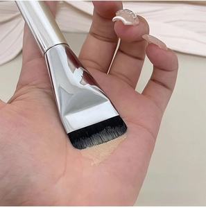 Macro shot of flat foundation brush showing uniform liquid distribution on palm