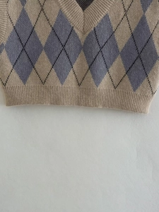Close-up of argyle knit vest featuring V-neck and ribbed texture in khaki and blue
