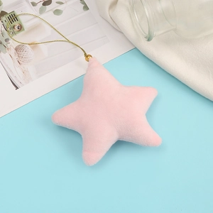 Detail of pink star plush ornament with golden cord on soft blue background