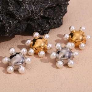 Macro detail of gold and silver wheel earrings with embedded white pearls on a rock