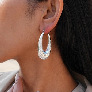 Close-up of a silver-toned oval hoop earring featuring a unique textured ripple design