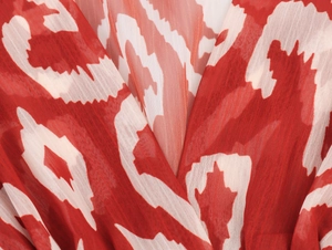 Vue macro du décolleté en V d'une robe longue en mousseline à imprimé géométrique rouge et blanc