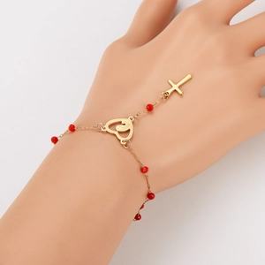 Golden heart and cross slave bracelet with vibrant red beads on a minimalist background