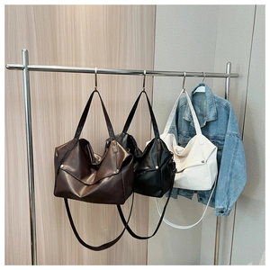 Detailed view of large leather tote bags in brown, black, and white with metal hardware