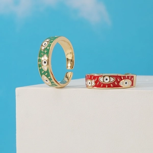 Detail view of gold-plated evil eye adjustable rings in red and green enamel finish