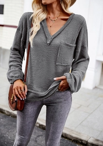Detail of grey waffle knit V-neck sweater featuring a front chest pocket and long sleeves