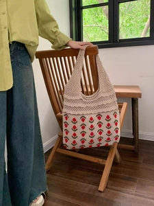 Close-up of handmade crochet tote bag featuring red strawberry patterns and ruffled layers