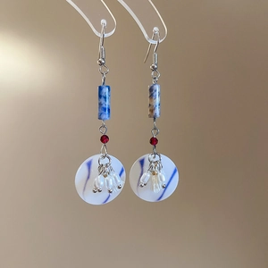 Close-up of vintage drop earrings with blue cylinder beads and white resin discs