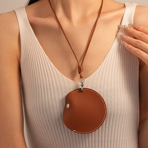 Detail of a brown leather pouch necklace with white stitching and silver snap button