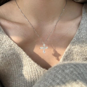 Detail of S925 sterling silver cross necklace with inlaid zircons on model neck