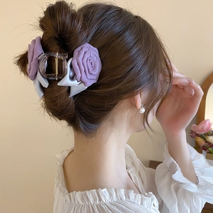 Détail d'une pince à cheveux rose en tissu violet portée sur un chignon élégant de mannequin