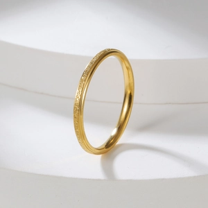 Detailed view of a 2mm gold frosted stainless steel ring on a white architectural stand