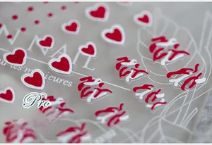 Detail of adhesive nail stickers with red heart patterns and artistic line designs