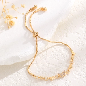 Detail of adjustable gold bracelet featuring butterfly charm and heart accents