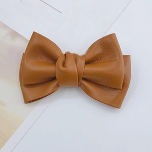 Macro detail of brown faux leather pleated bow with rich texture for DIY accessories