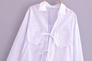 Détail de la blouse blanche avec poches à volants et fermetures à nouer délicates