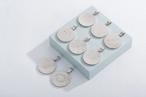 Close-up of assorted silver stainless steel round pendants with engraved quotes and symbols