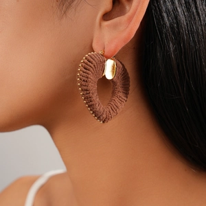 Close-up of brown fabric-wrapped heart earring with gold accents on model ear