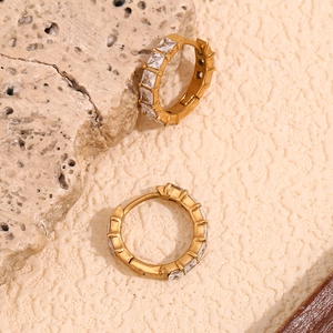 Détail macro de créoles plaquées or 18 carats ornées de zircons blancs carrés