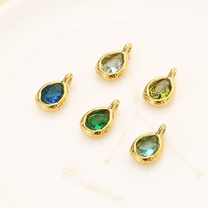 Close-up of teardrop stainless steel pendants with faceted colorful birthstones on a dish