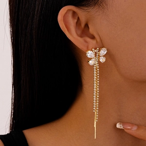 Detailed close-up of golden butterfly earrings with crystal tassels on a model
