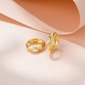Macro shot of gold-plated hoop earrings featuring inlaid cubic zirconia on a warm background