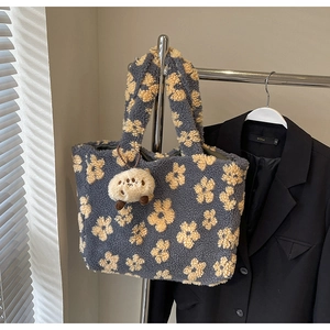 Close-up of floral plush tote bag with a cute sheep keychain on a metal hanger