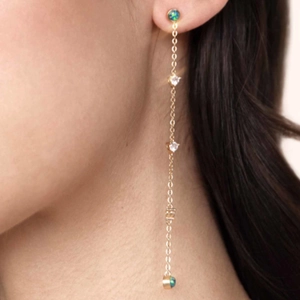Detail of long gold tassel earrings with opal stones and crystals on a model