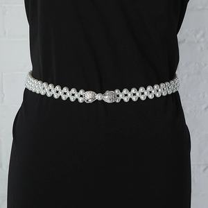 Detail of elegant white pearl waist chain with a silver rhinestone bow buckle on a dress