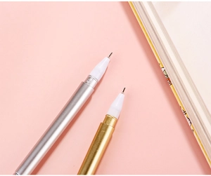 Macro detail of gold and silver metallic pens with fine needle tips on pink background