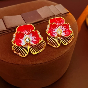 Vintage flower earrings with red enamel petals and pearls on a velvet jewelry box