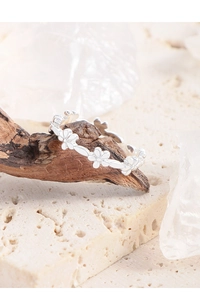 Detailed close-up of a silver flower cluster ring displayed on a natural wooden branch