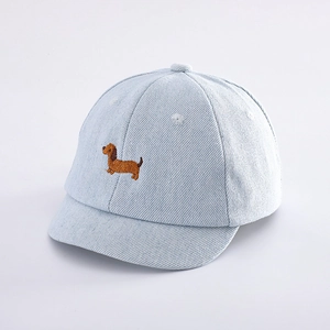 Close-up of light blue denim baby baseball cap with brown dachshund dog embroidery