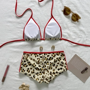 Flat lay of a leopard print bikini set with red trim and summer vacation accessories