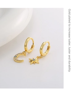 Macro shot of gold plated asymmetric star and moon earrings with blue cubic zirconia