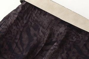 Detalle de la tela con estampado de leopardo y un cinturón beige en un vestido midi
